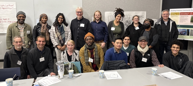A group of people pose for a photo in a classroom setting following a Community Sounding Board meeting.