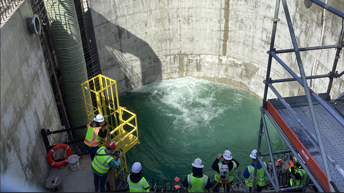 Construction workers observe water entering a large concrete shaft during a breakthrough at the Ship Canal Water Quality Project site.