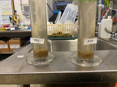 Two measuring tubes labeled RAS and AER in a lab.