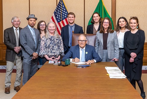 Katie Hurley (far right) among coalition partners with Gov. Jay Inslee as he signs DPD-backed legislation