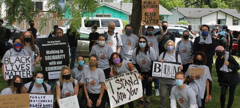 Photo of the Department of Public Defense team holding signs during a protest.