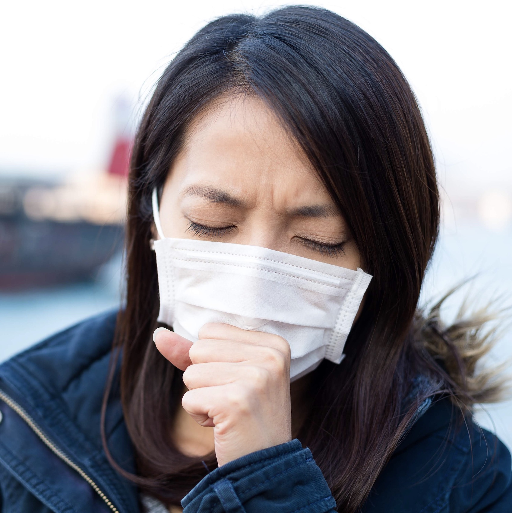 Woman coughing while wearing a face mask