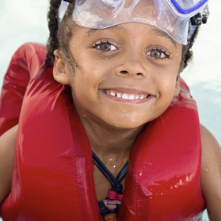 Child swimming with life jacket and goggles