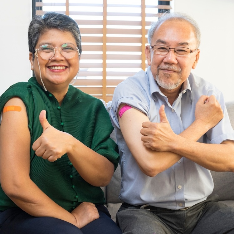 An elderly Asian couple with thumbs up after having received vaccine