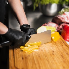 cutting peppers on a cutting board while wearing gloves created by freepik.com