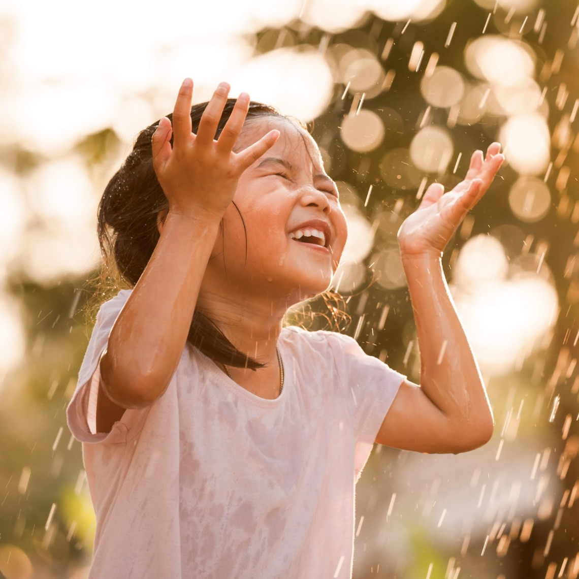 Young girl playing in a sprinkler on a hot day