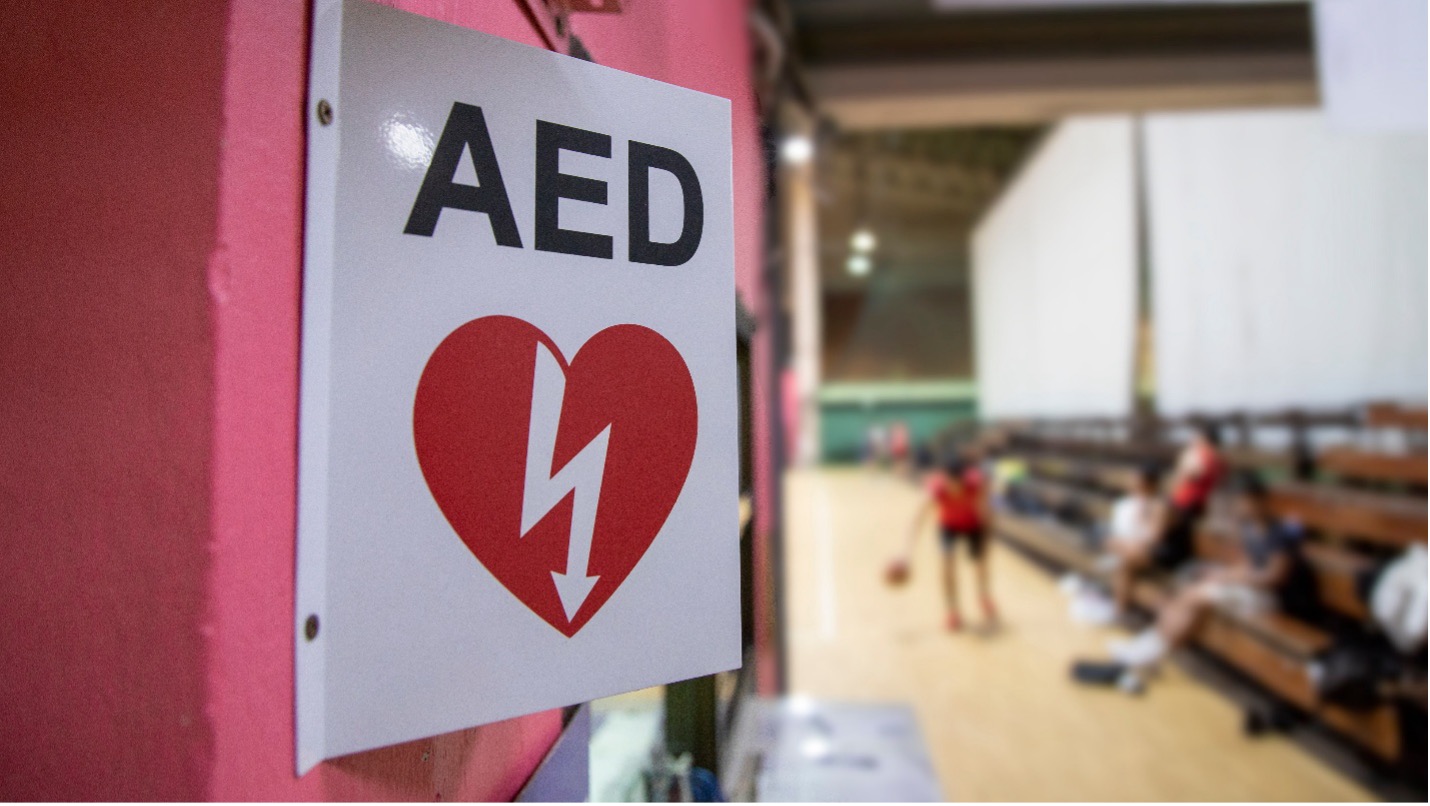 Metal AED sign posted in a public space to indicate that an AED device is available there.