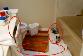 Image of a bathroom scene showing hazards that could make one fall and injure themselves including bath rugs, clothing and open drawers