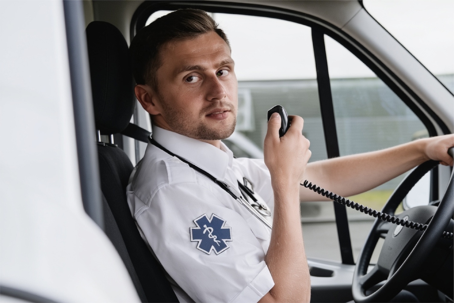 A paramedic in the driver's seat of a Medic One rig while using a dispatch device.