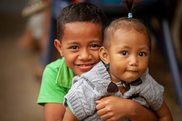 A young boy hugging his baby sister