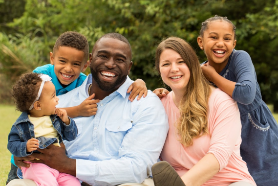 A family of five smiling in a park