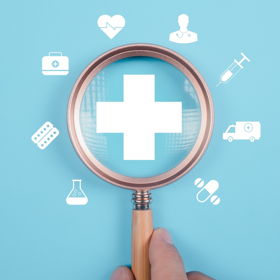 Symbolic focus of health care services with hand holding a magnifying glass focused on various health care icons