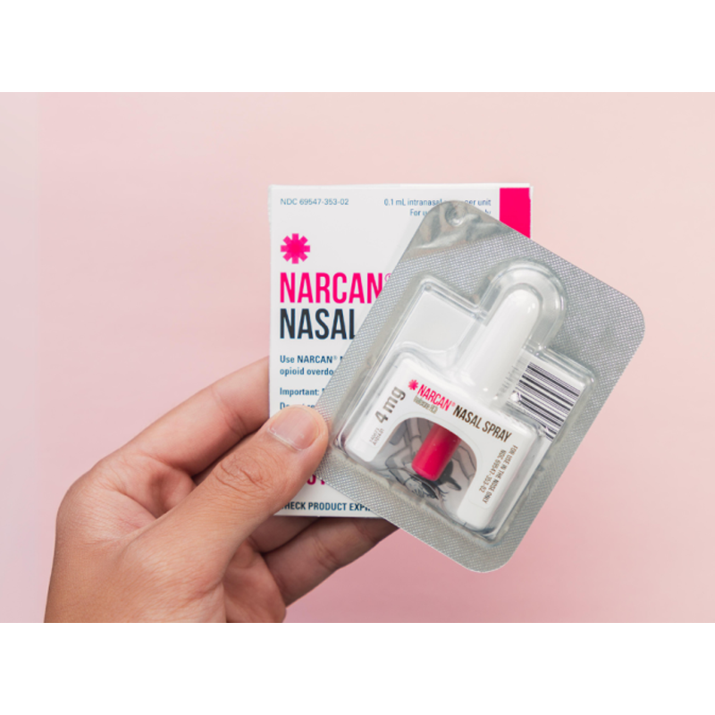 a hand holding a narcan inhaler in a package