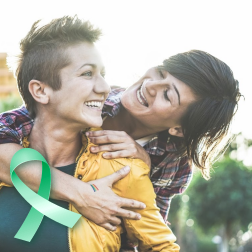 Two women with a green ribbon representing early detection with cervical cancer screening
