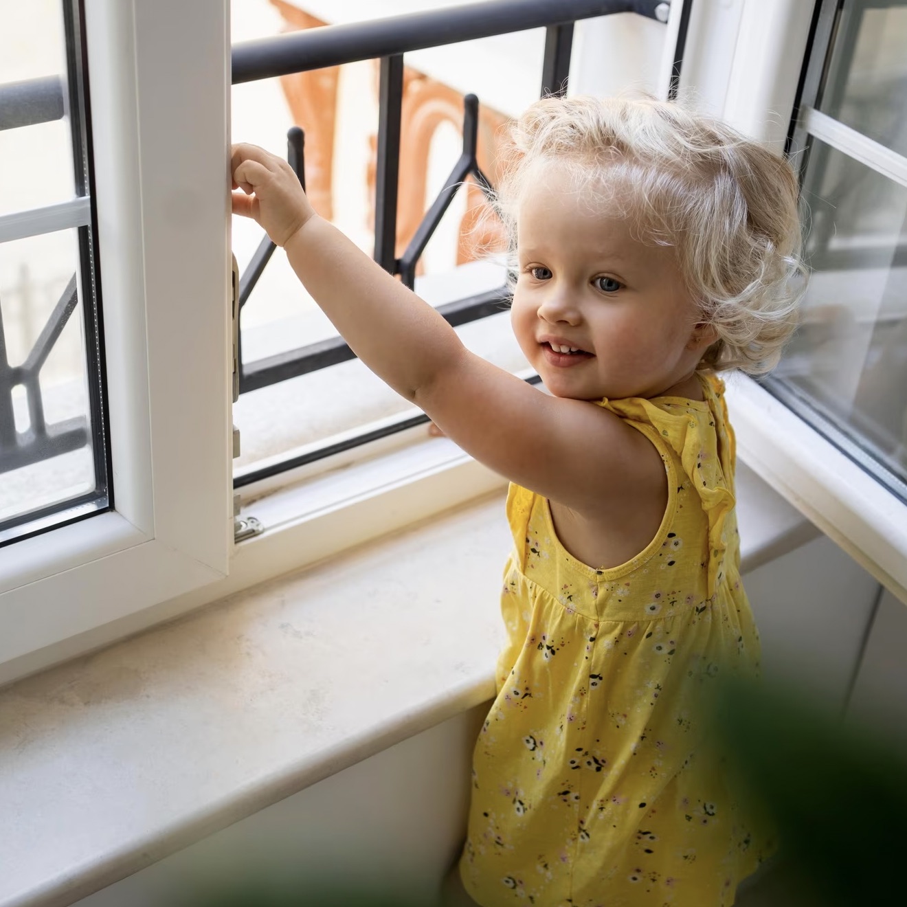 Toddler girl at open window with protective railing