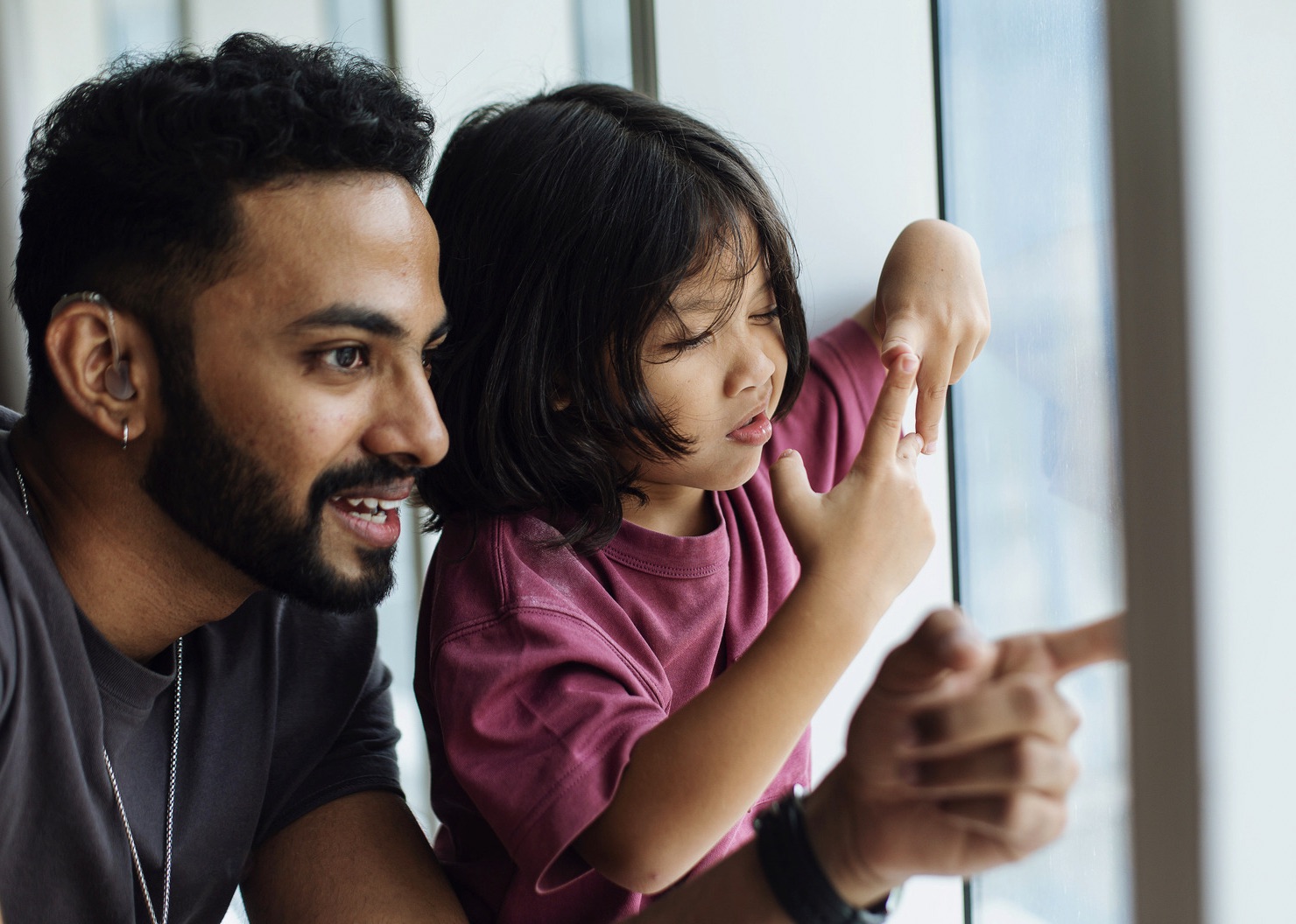 Male parent supervising daughter at a window