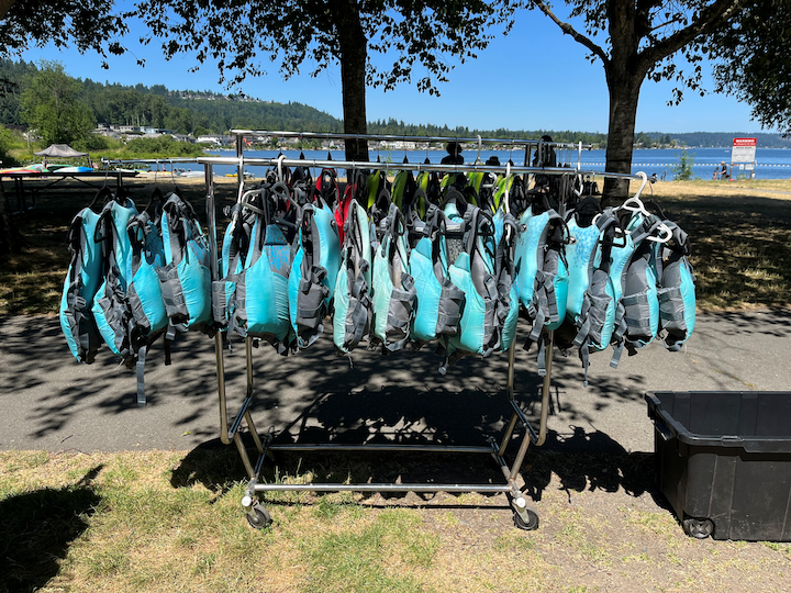 A rack of light blue and black lifejacket available to loan