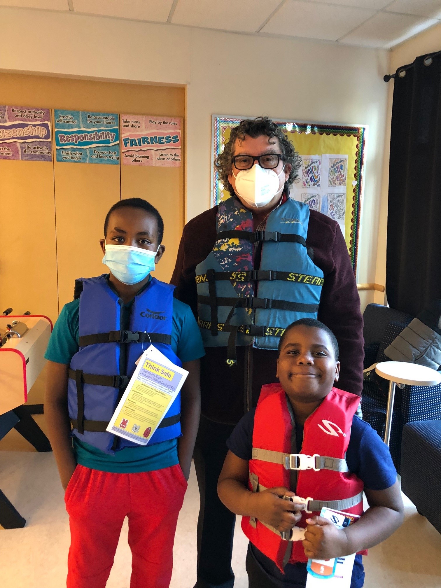 Tony Gomez, Manager of King County Violence and Injury Prevention and two boys wearing life jackets at a water safety event