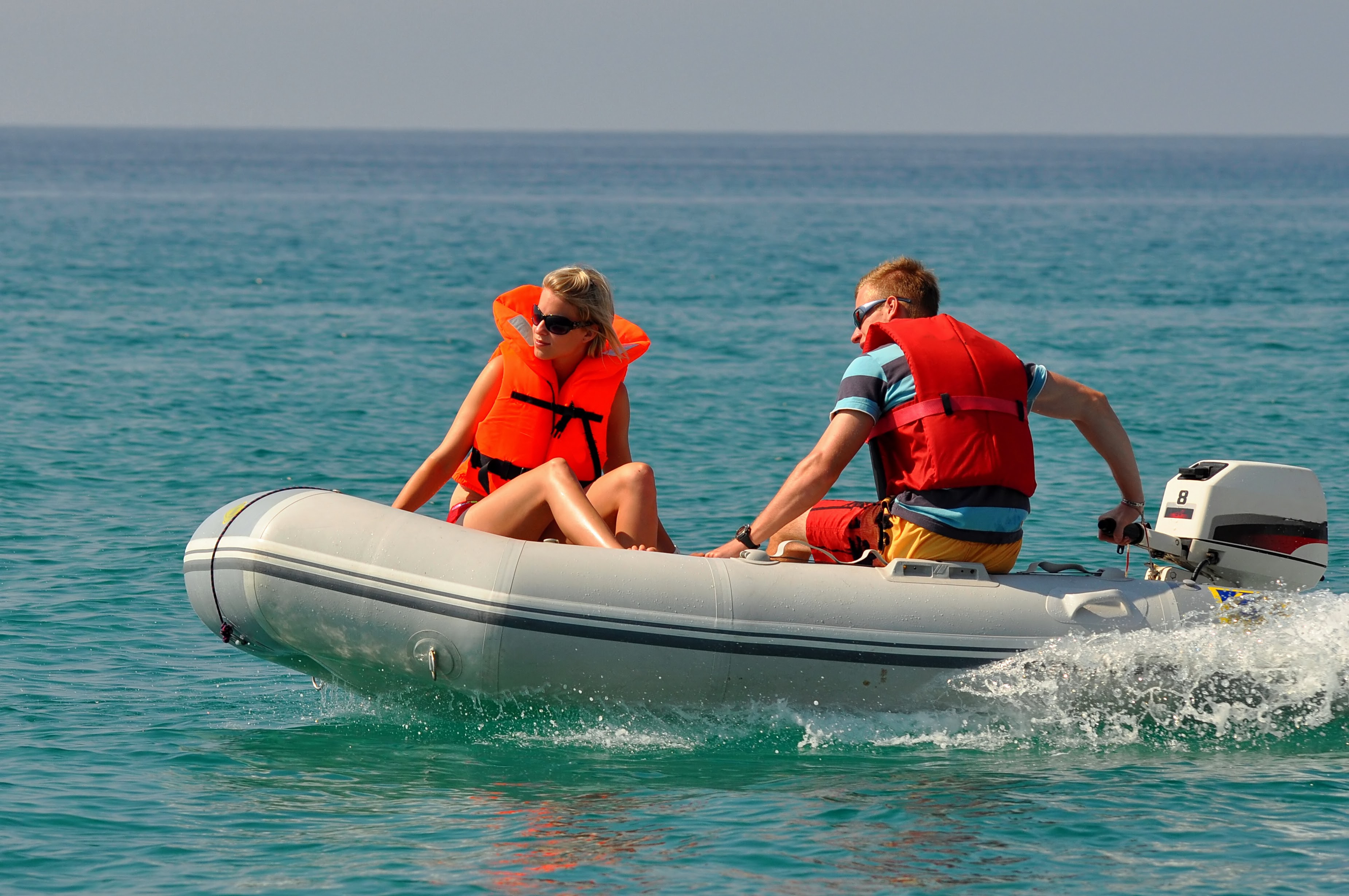 Two people in a motorized inflatable boat wearing life jackets