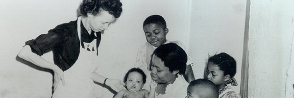 Person smiling down at a group of children and their mother