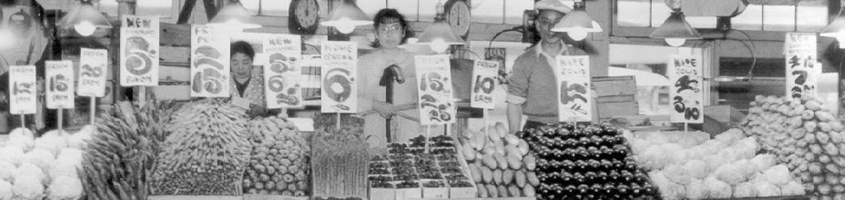 Row of people standing behind vegetable stands at a market