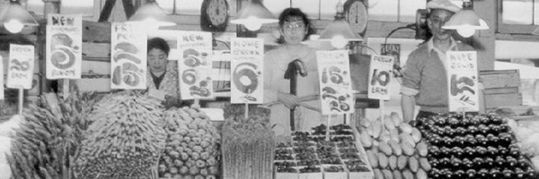 people standing behind stalls of fruits and vegetables