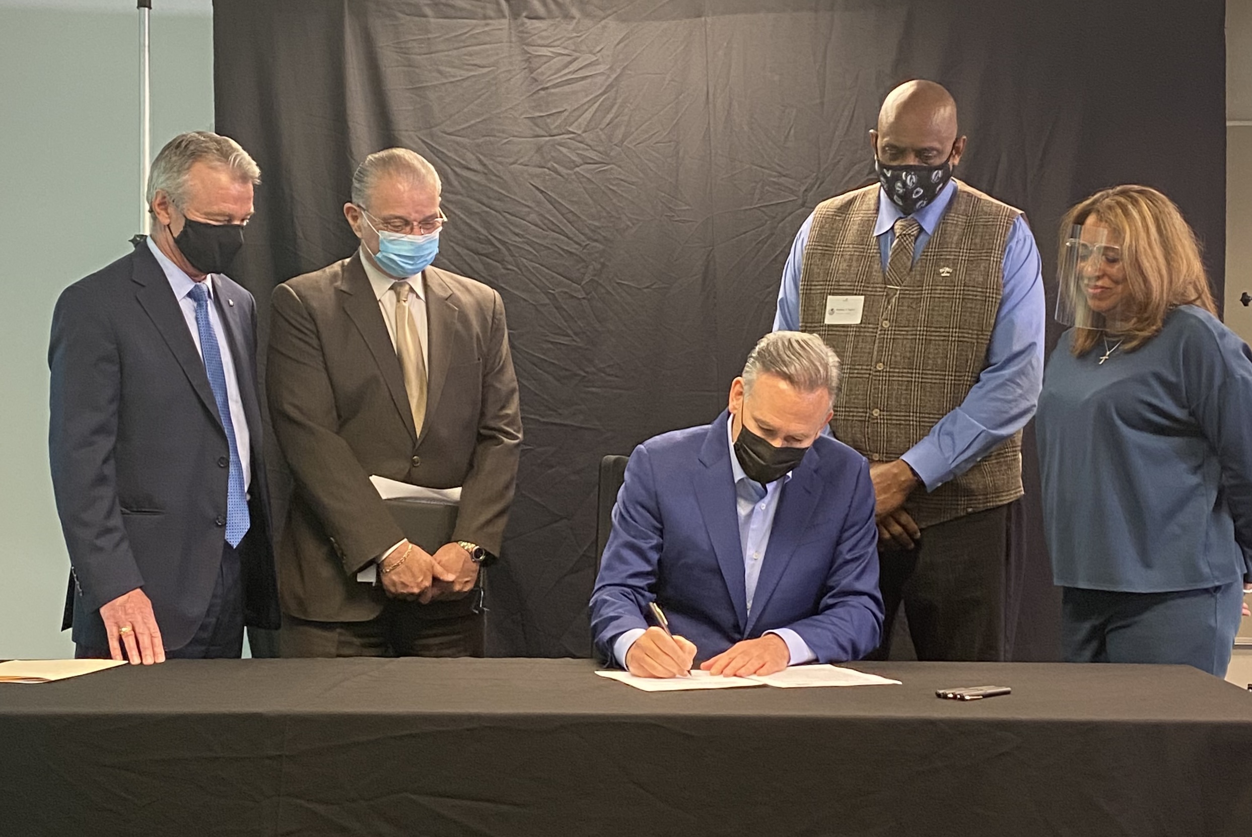 King County Executive Dow Constantine surrounded by three other people as he signs an order