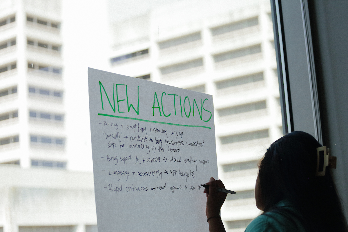 person writing on paper that says new actions