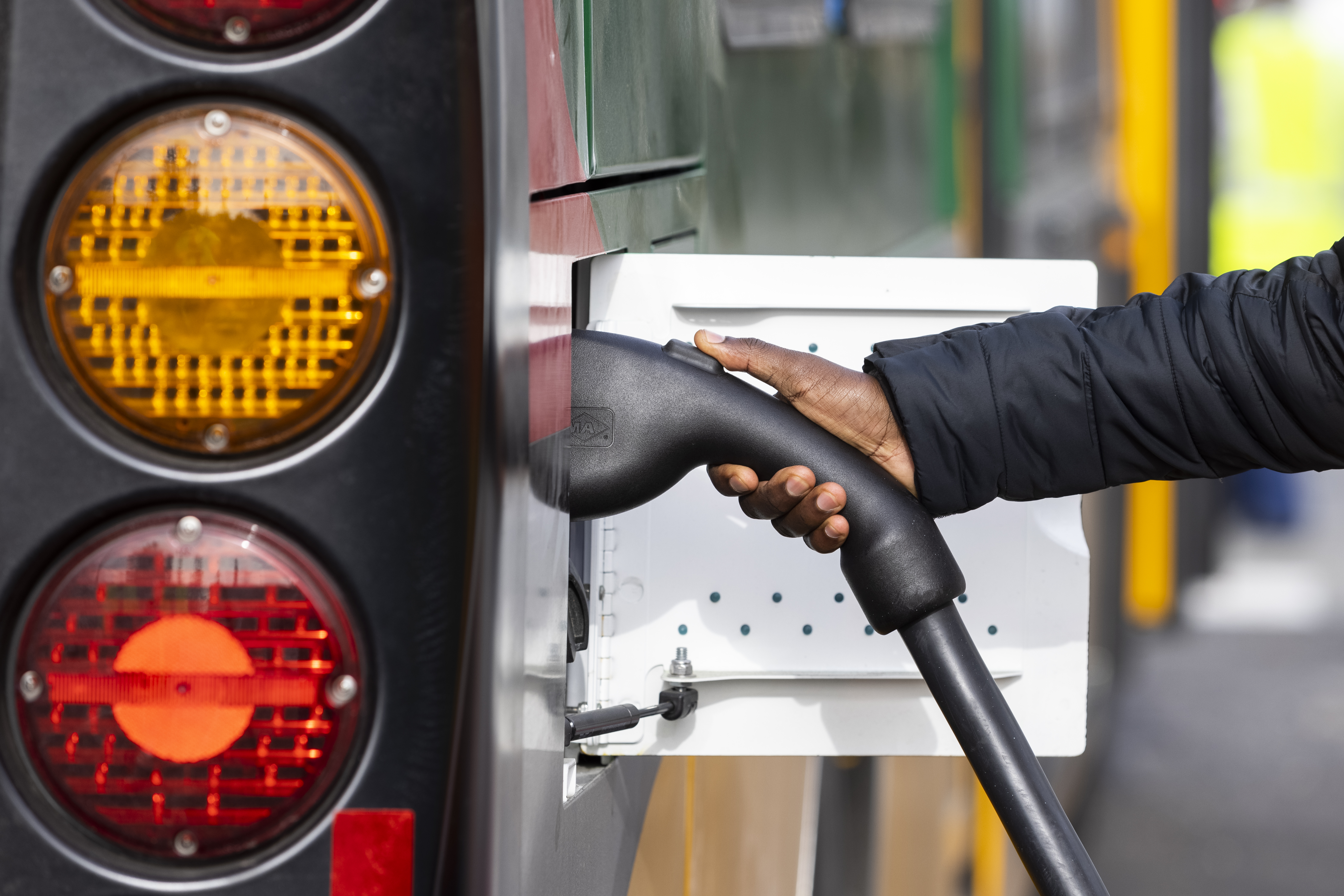 person holding electric charger to bus