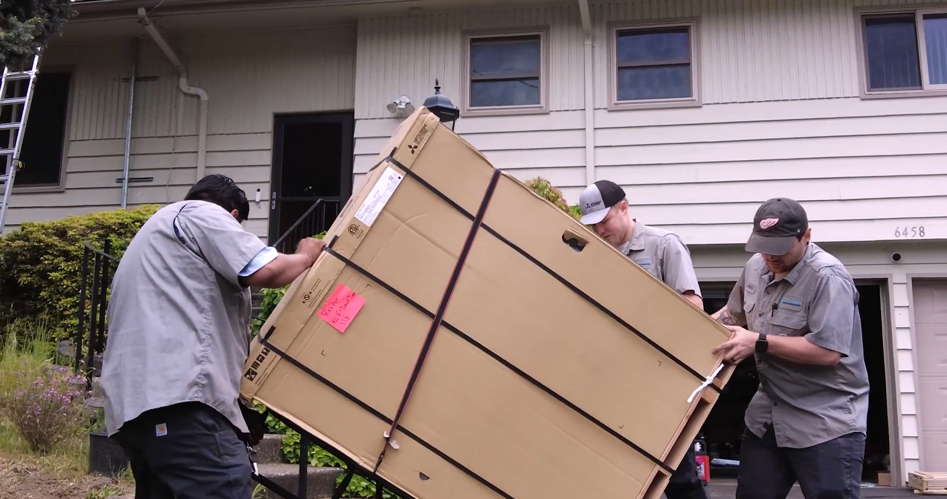 workers hold box while installing heat pump