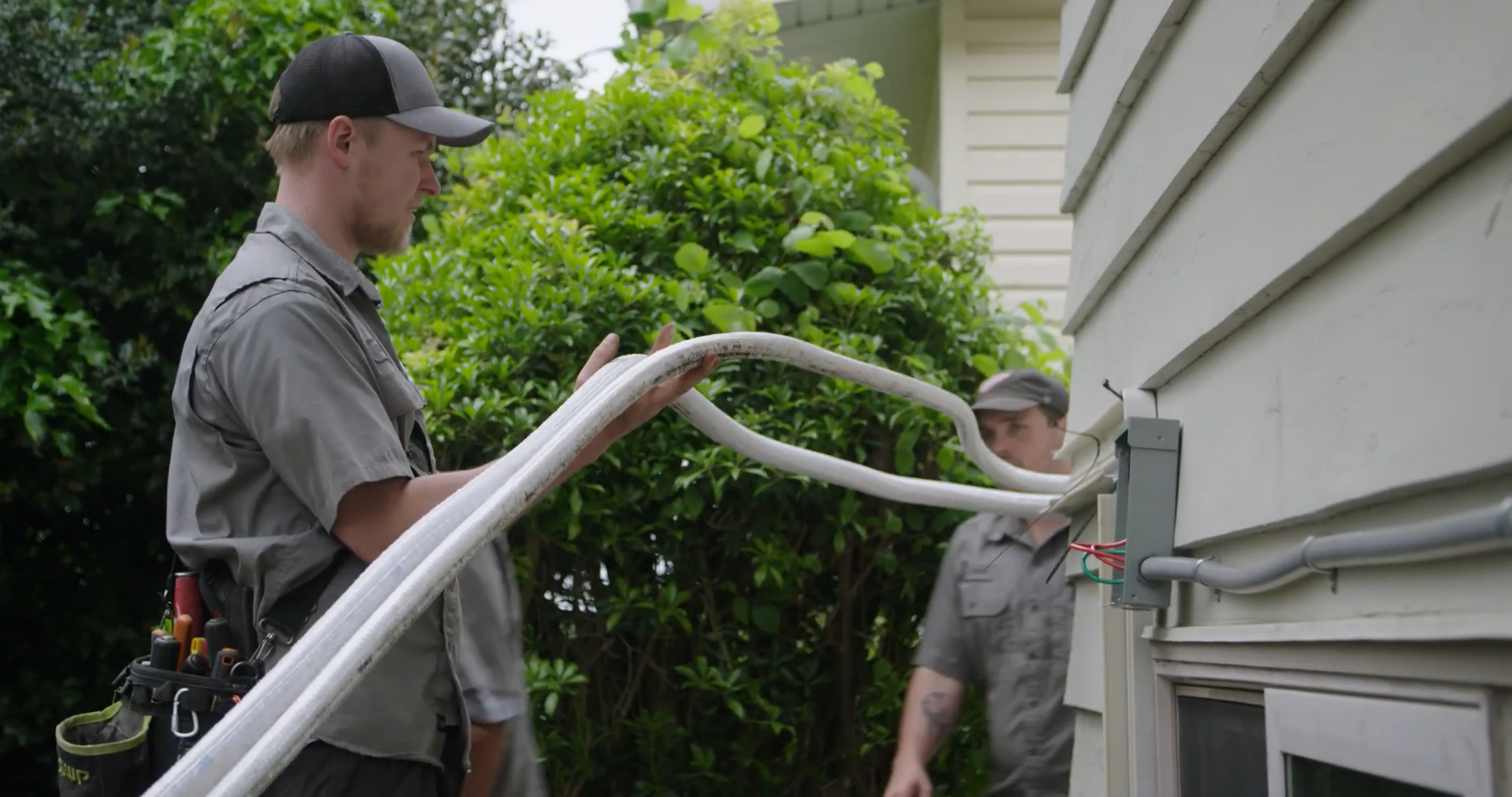 person holding tubes while installing heat pump