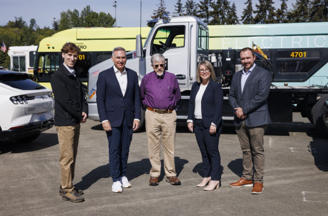 group of people smiling in front of an electric vehicle