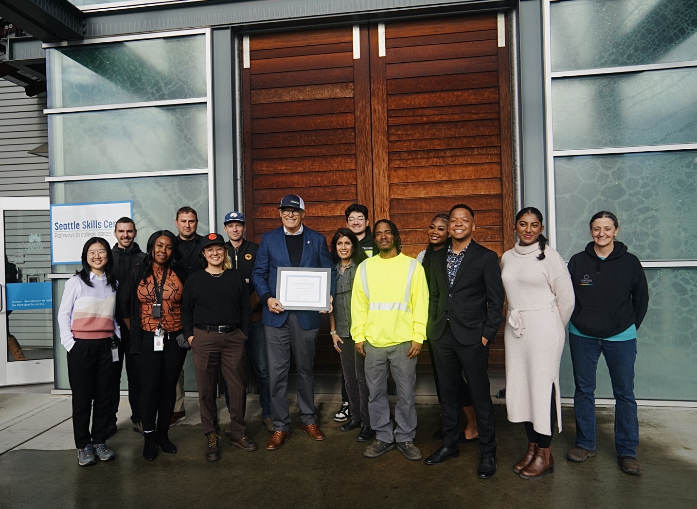 Group of people smiling in front of the Wood Technology Center. 