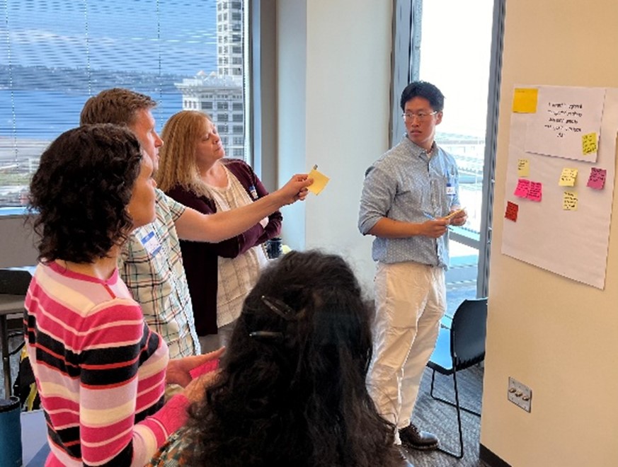 People gathered around poster board with post-it notes on it