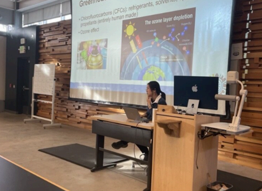 person sitting behind desk in front of projector screen