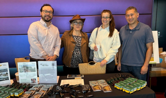group of people posing for photo, standing behind brochures and flyers