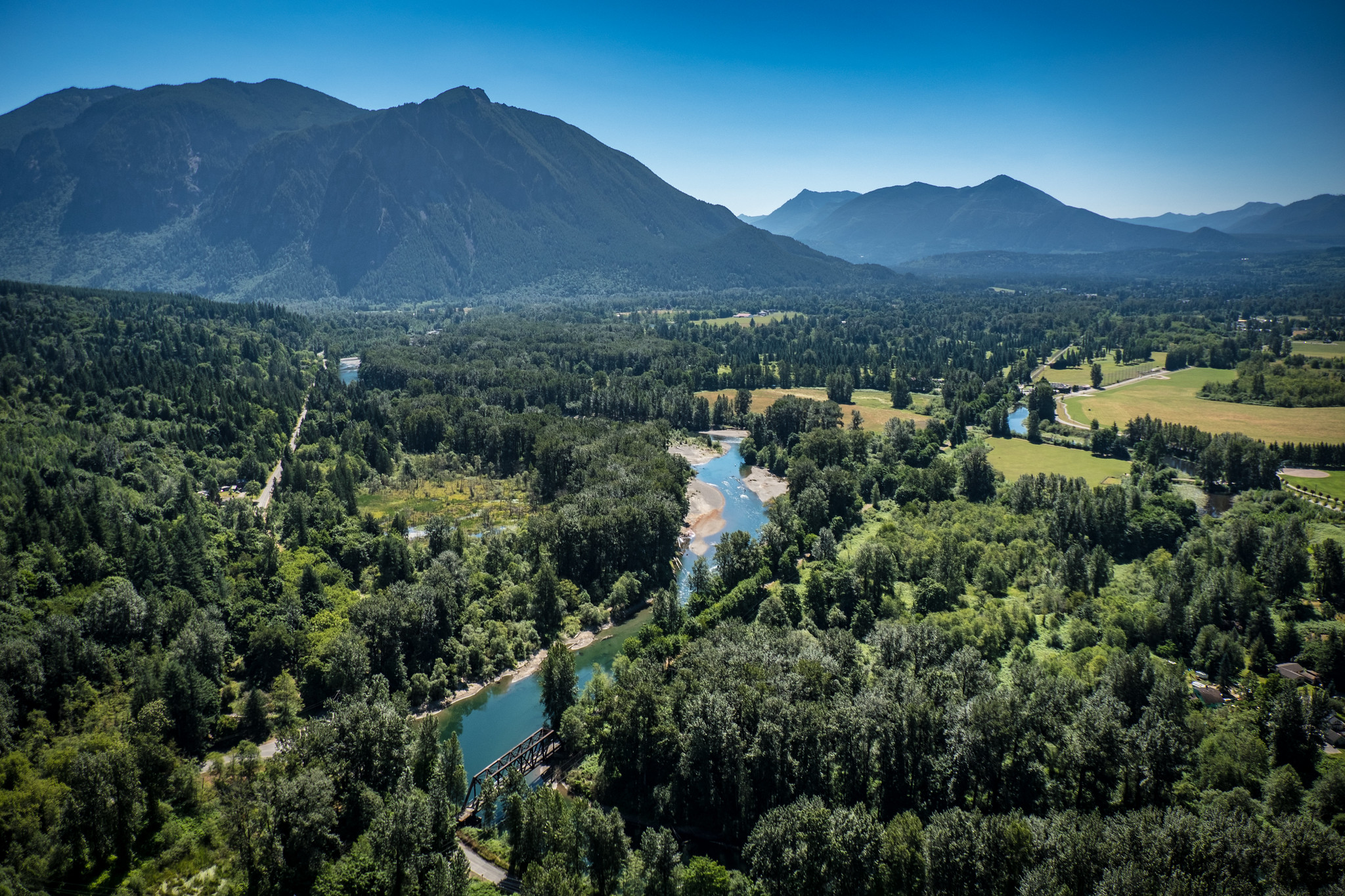 An aerial photo of a river running through a valley flanked by mountains.