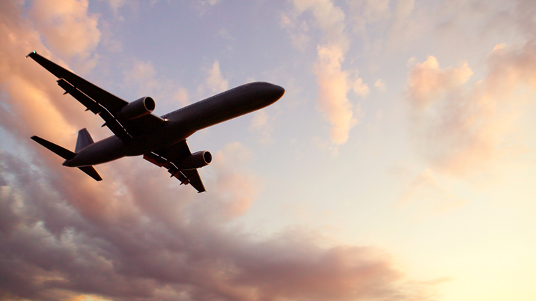 A commercial airplane viewed from below during sunset. The Aerospace sector is a major and indispensable source of family wage jobs and economic strength for the Puget Sound region.
