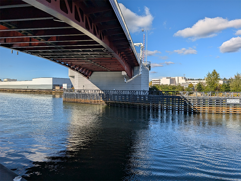 View from waterlevel looking up at South Park Bridge with blue skies and clouds.