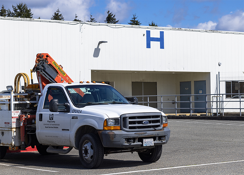 Main entrance to the Map and Record Center in H Building on the Road Services Renton Headquarters campus. Roads Maintenance truck parked out in front of building.