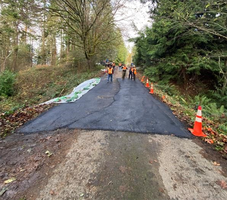 Crews standing on asphalted road.