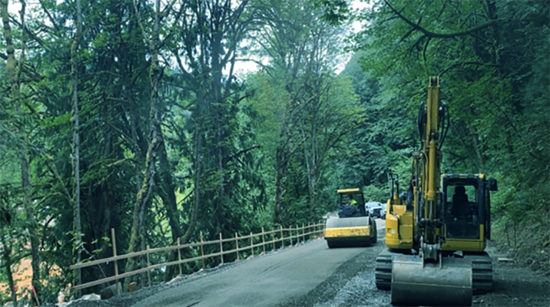 Crews using a drum roller compactor. 