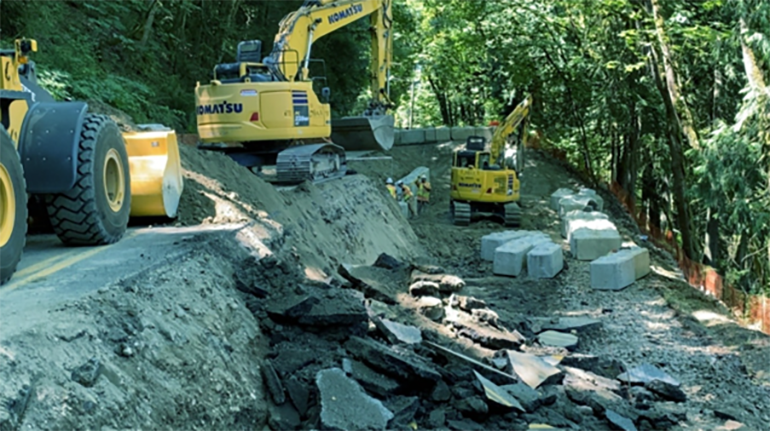 Excavated unstable soil is removed below the road to prepare for solider pile installation.