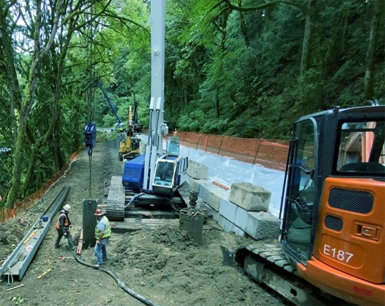 Workers place a steel beam, known as a "soldier pile," deep into the ground. This beam helps keep the ground stable and stops the soil from moving around.   July