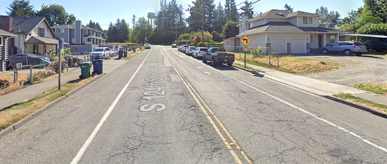 Photo of cracked roadway with Google maps S 124th St displayed vertically on roadway.