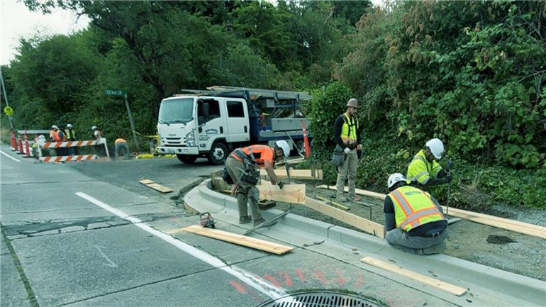 Roads crew workers install a new ADA compliant curb.