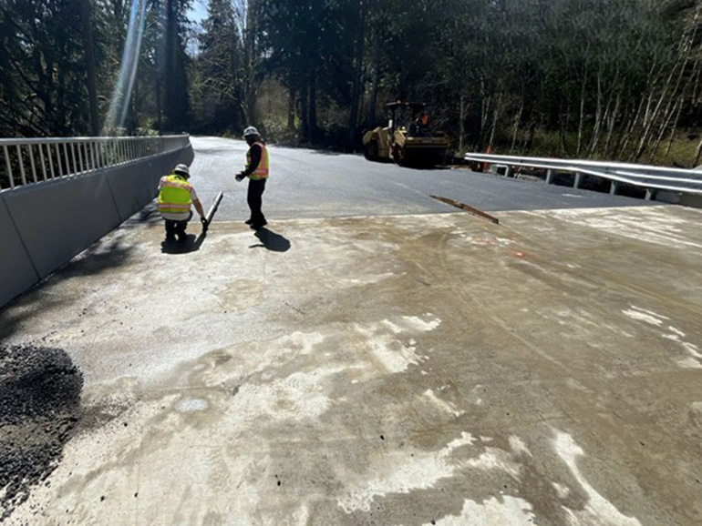 Crewmembers use levels to ensure a seamless transition between the newly paved road and the concrete bridge deck. 