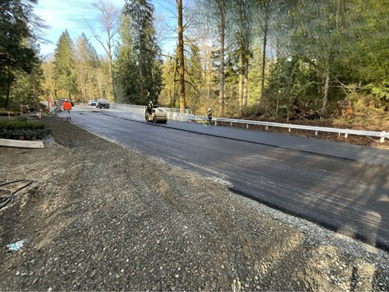 A crewmember uses a rolling compactor to press asphalt evenly and firmly onto the road surface. 