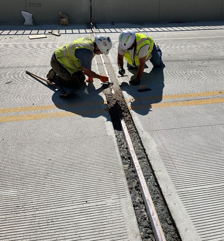 Crew members fill the space around the expansion joint after replacement. This allows for movement of the surrounding concrete while preventing issues such as water penetration and weed growth.