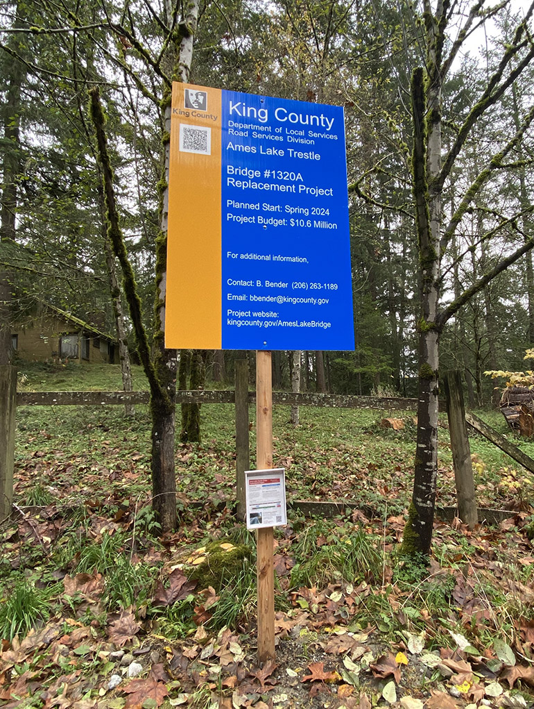 Official blue and yellow Ames Lake Trestle Bridge Project information signs
